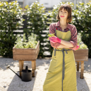 woman standing in her home garden, wearing an apron looking satisfied that she is selling produce with UrbeeFresh